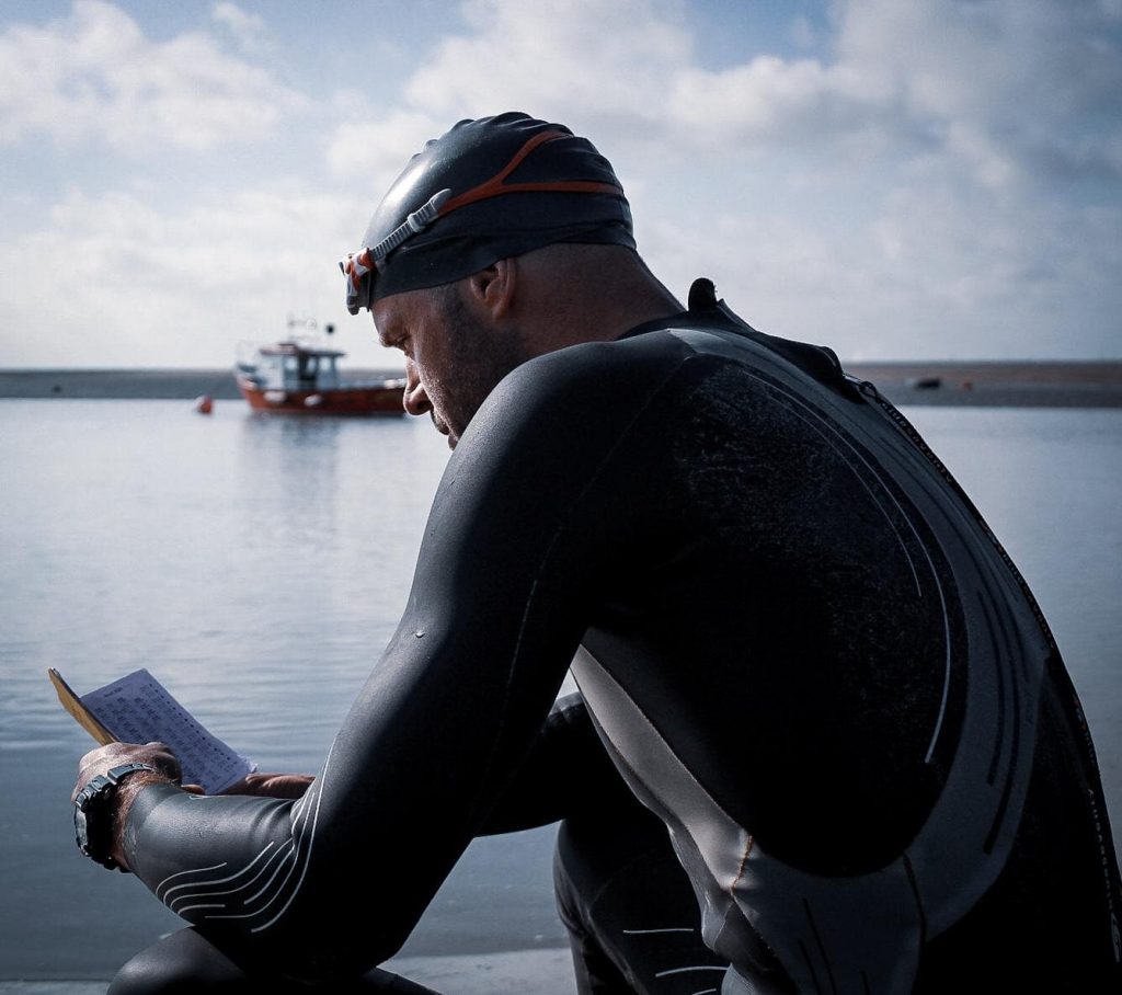 Mat Hawkes wearing a wetsuit and reading a book